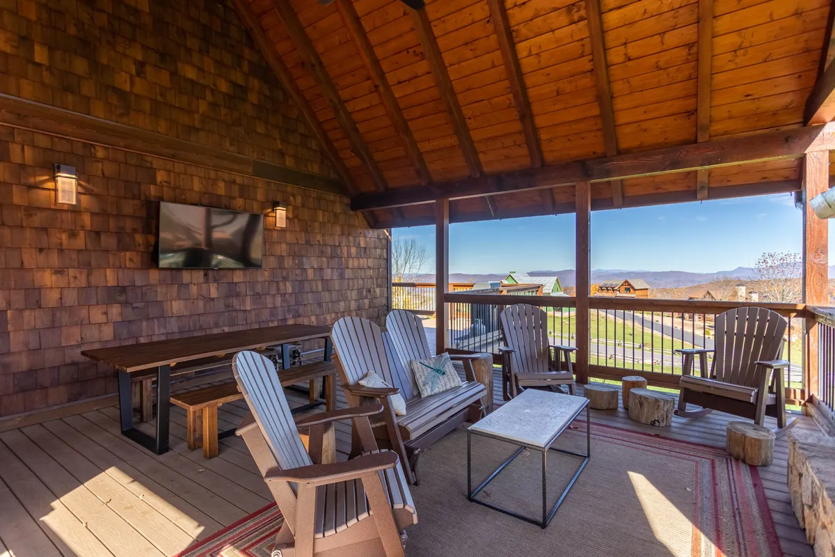 This image showcases comfortable wooden seating and an outdoor table on a patio with a panoramic mountain view. The cozy scene suggests relaxation and socializing while immersed in nature, perfect for gatherings or unwinding after a day of activity.