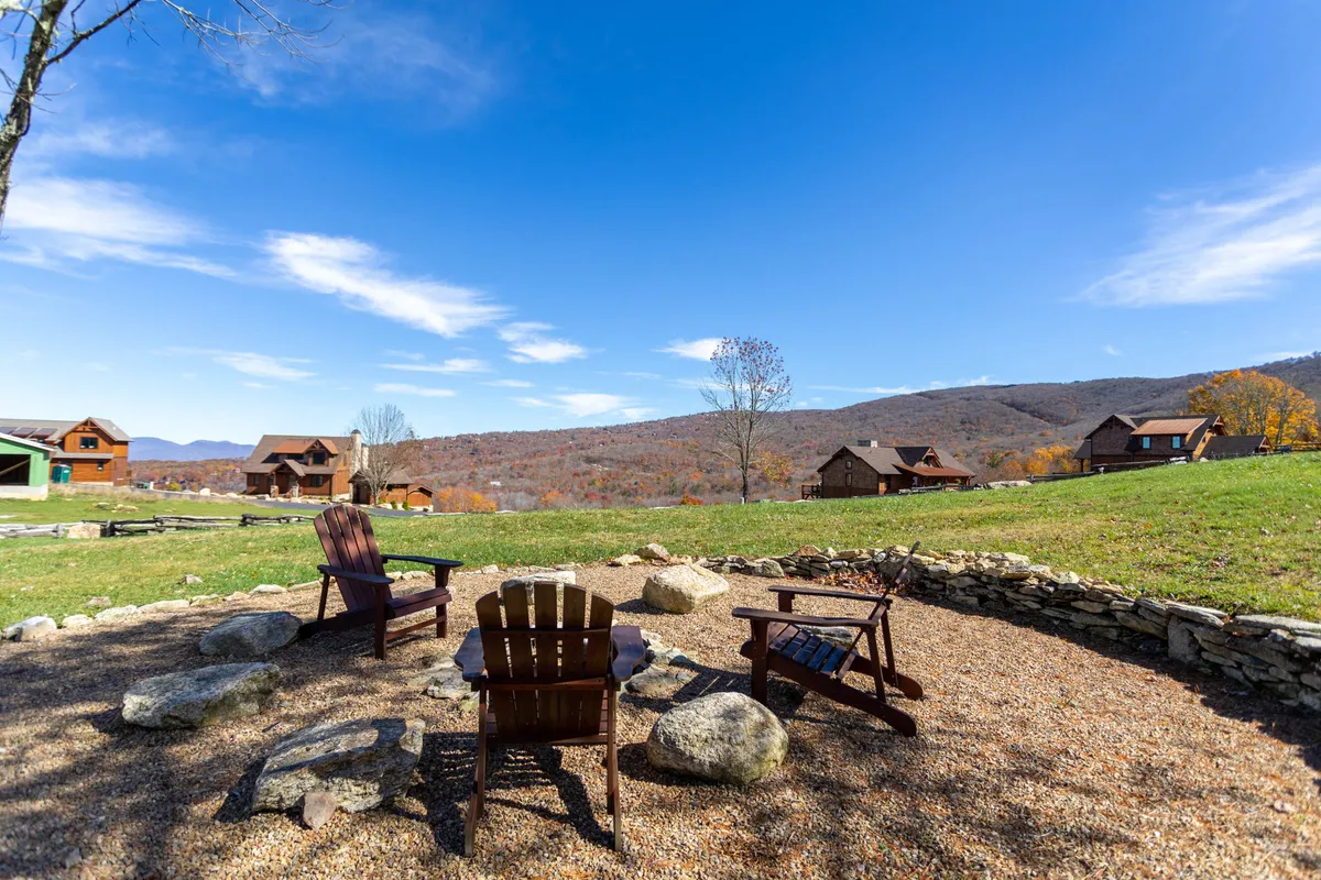 This peaceful exterior image highlights a circle of wooden chairs around a rock firepit, facing out to the mountains. The tranquil setting is ideal for group stories, evening fires, and connecting under the stars.