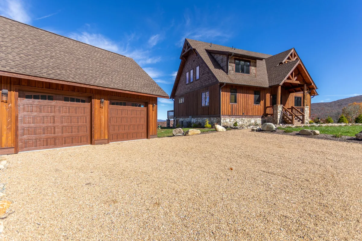 The exterior showcases a wooden house with a landscaped yard and garage. The porch and open lawn offer plenty of space for outdoor activities, relaxation, and group gatherings, reflecting a casual, festive atmosphere.